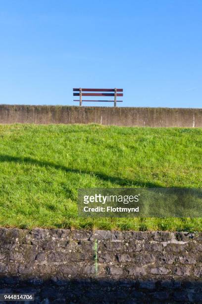 bench on top of a dyke in doel, belgium - doel stock pictures, royalty-free photos & images