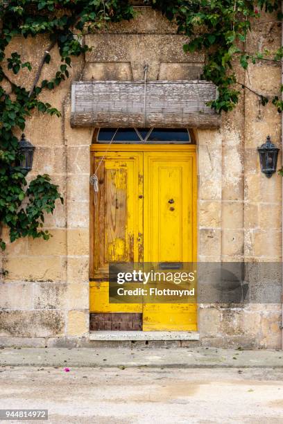 weathered yellow door in st lucija in gozo, malta - doppeltür stock-fotos und bilder