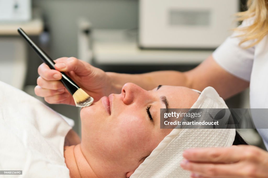 Young woman receiving a facial treatment in beauty spa.