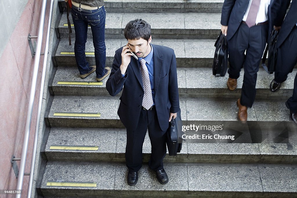 Businessman standing on steps talking on cell phone