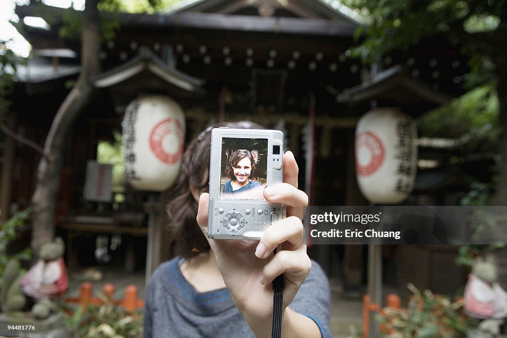 Woman holding up self-portrait in digital camera, Japan