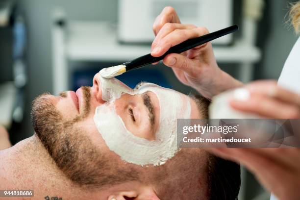 young man receiving a facial treatment in beauty spa. - man make up stock pictures, royalty-free photos & images