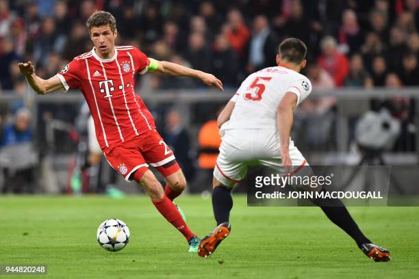 Bayern Munich's German forward Thomas Mueller and Sevilla's French defender Clement Lenglet vie for the ball during the UEFA Champions League...
