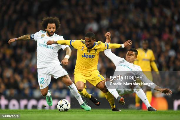 Douglas Costa of Juventus is challenged by Marcelo of Real Madrid and Casemiro of Real Madrid during the UEFA Champions League Quarter Final Second...