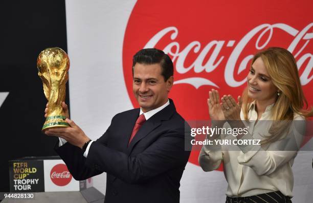 Mexico's President Enrique Pena Nieto accompanied by his wife Angelica Rivera holds the FIFA World Cup trophy while it is displayed at the...