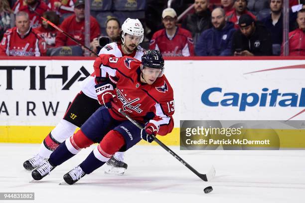 Jakub Vrana of the Washington Capitals controls the puck against Erik Karlsson of the Ottawa Senators in the first period at Capital One Arena on...