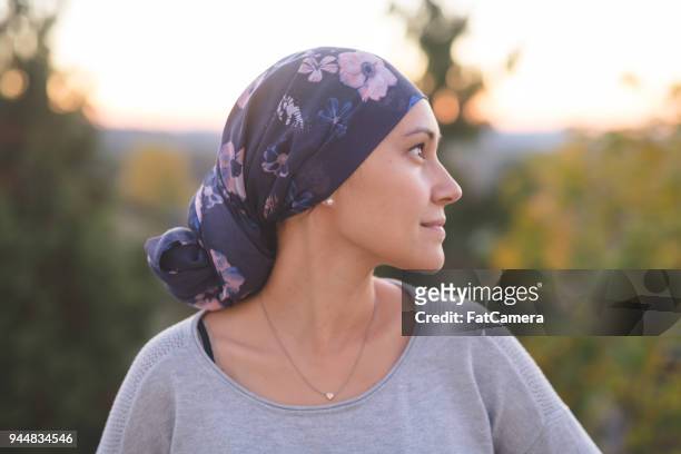 étnica mujer luchando contra el cáncer se encuentra fuera y contempla su vida - manage fotografías e imágenes de stock