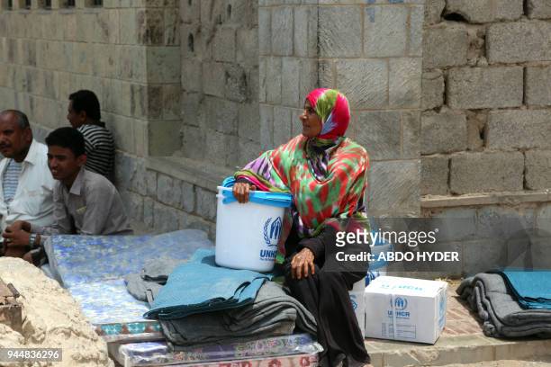 Yemeni woman sits next to blankets and upholstery distributed by the UN High Commissioner for Refugees to those affected by the conflict in the...