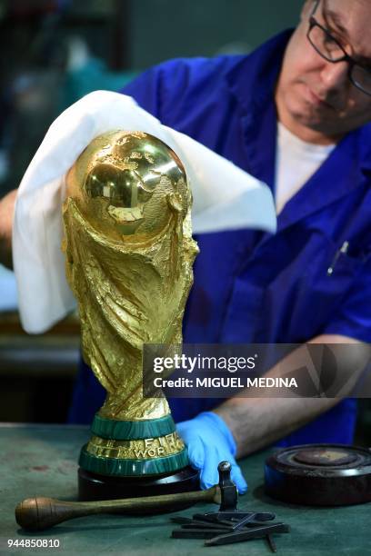 An artisan operator cleans with a cloth a replica of the FIFA football World Cup Trophy at the Italian trophy and medal manufacturer GDE Bertoni on...