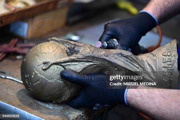 An artisan operator does the frosting on a raw trophy, replica of the FIFA football World Cup Trophy, at the Italian trophy and medal manufacturer...