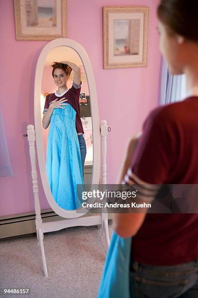 teenage girl holding dress in front of mirror. - prom dress stock pictures, royalty-free photos & images