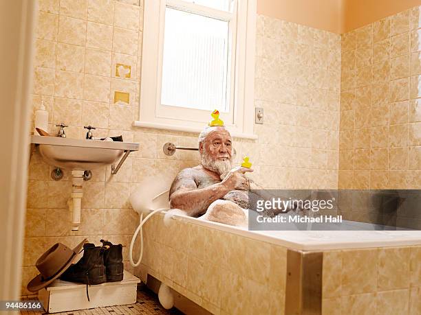 man in bath with rubber ducky - badeend stockfoto's en -beelden