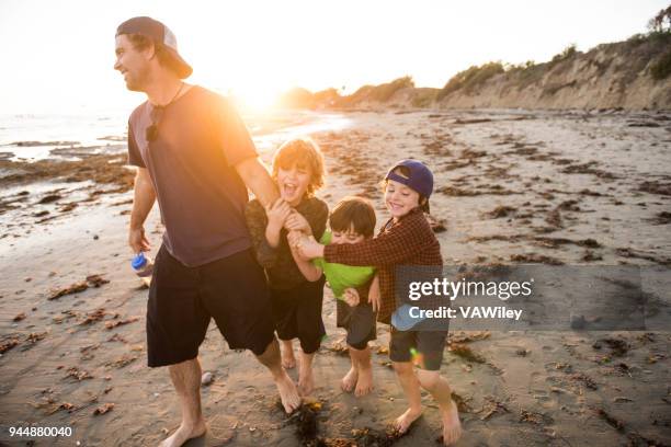 kinder spielen mit ihrem vater am strand - rough housing stock-fotos und bilder