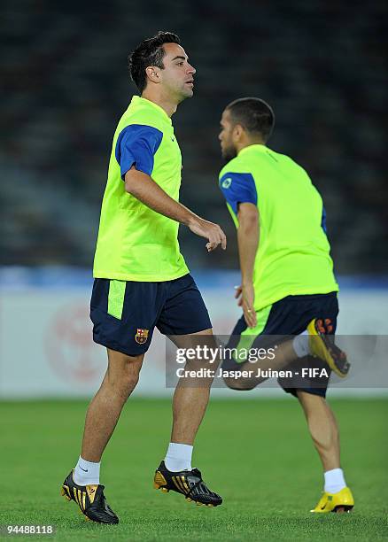 Xavier Hernandez of FC Barcelona excercises backdropped by his teammate Daniel Alves during a training session at the Zayed Sports City stadium on...