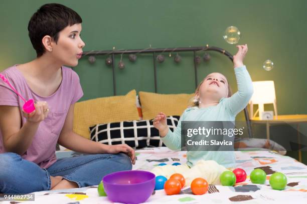 mother and daughter playing with soap bubbles - catching ball stock pictures, royalty-free photos & images