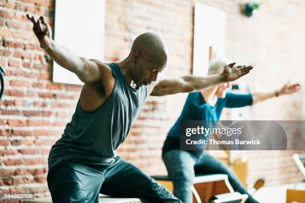 mature man practicing on pilates chair during class in fitness studio - well structure stock pictures, royalty-free photos & images