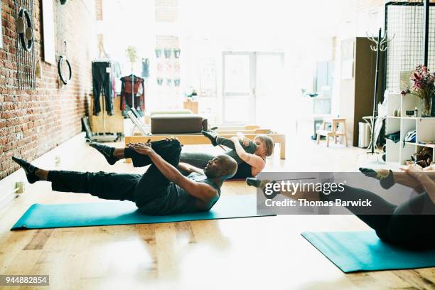 mature male pilates student practicing single leg mat stretch during class in pilates studio - mat stock pictures, royalty-free photos & images