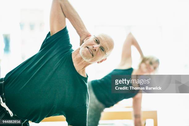 Smiling mature man exercising during pilates class in fitness studio