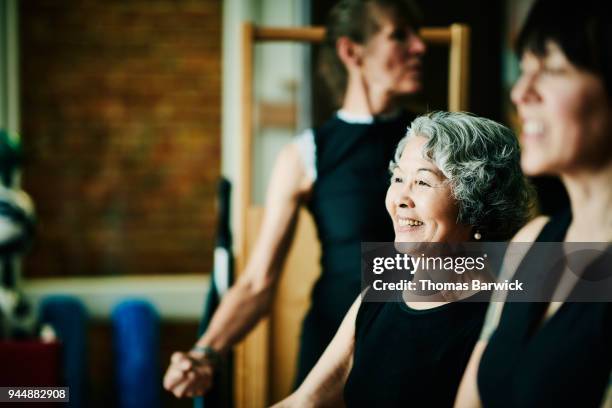 smiling mature woman hanging out with friends in pilates studio while resting between exercises - people diversity friends multi ethnic smiling indian ethnicity stock pictures, royalty-free photos & images