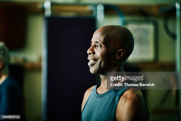 portrait of smiling mature male pilates instructor leading pilates class in fitness studio - adult male vest exercise stock pictures, royalty-free photos & images