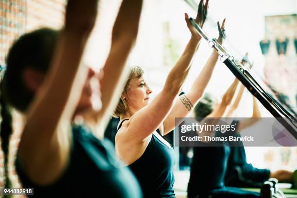 woman using reformer arm straps during pilates class in fitness studio - pilates gerät stock-fotos und bilder