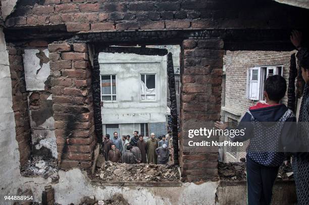 Kashmiri civilians check the burnt houses where rebels took the shelter while fighting with the government forces Wednesday, April 11 in Khudwani...