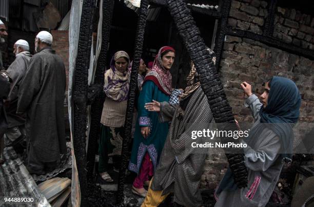 Kashmiri civilians check the burnt houses where rebels took the shelter while fighting with the government forces Wednesday, April 11 in Khudwani...