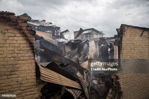 Kashmiri civilians search the debris of a house after a gunfight between rebels and government forces Wednesday, April 11 in Khudwani village about...