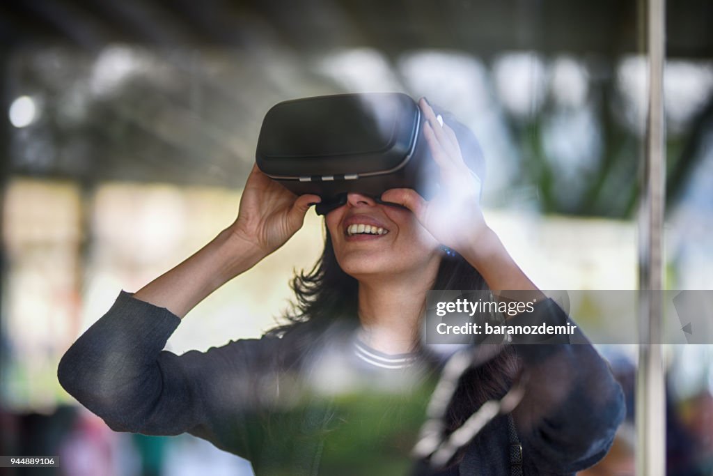 Mujer joven mirando con VR tras el cristal