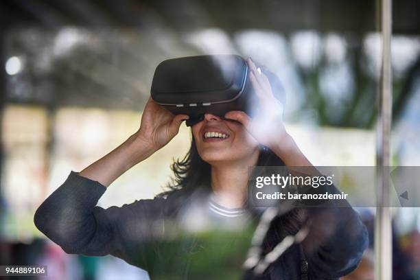 young woman looking with vr behind the glass - vr stock pictures, royalty-free photos & images