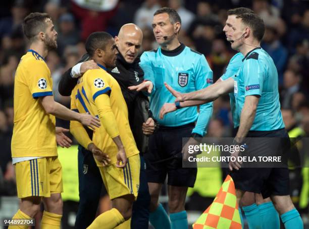 Juventus' Brazilian forward Douglas Costa argues with referees during the UEFA Champions League quarter-final second leg football match between Real...