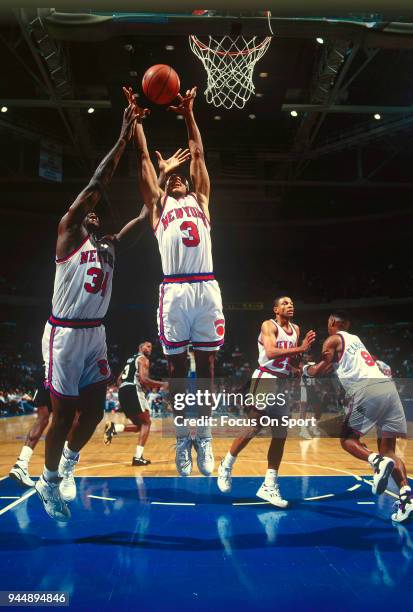 John Starks and Charles Oakley of the New York Knicks battles for a rebound against the San Antonio Spurs during an NBA Basketball game circa 1992 at...