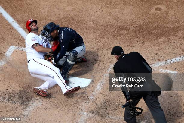 Catcher Kurt Suzuki of the Atlanta Braves tags out Matt Adams of the Washington Nationals at home plate for the third out of the seventh inning as...