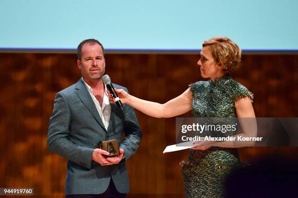 Host Caren Miosga and winner of the 'Staged Photography' Award Adam Ferguson speak on stage at the Nannen Award 2018 at Elbphilharmonie on April 11,...