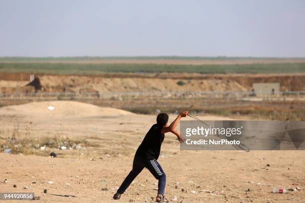 Palestinian protester uses a sling shot during clashes with Israeli toops near the border with Israel in the east of Jabaliya refugee camp in the...