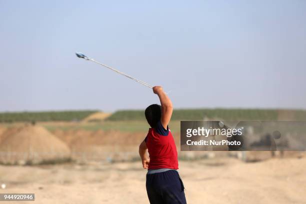 Palestinian protester uses a sling shot during clashes with Israeli toops near the border with Israel in the east of Jabaliya refugee camp in the...