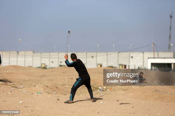 Palestinian protester uses a sling shot during clashes with Israeli toops near the border with Israel in the east of Jabaliya refugee camp in the...