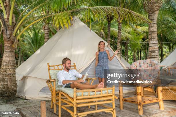 junges paar entspannende in glamping zeltplatz in tropische landschaft - glamping stock-fotos und bilder