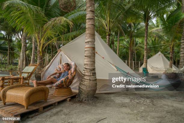 young couple relaxing in glamping campground in tropical scenery - luxury tent stock pictures, royalty-free photos & images