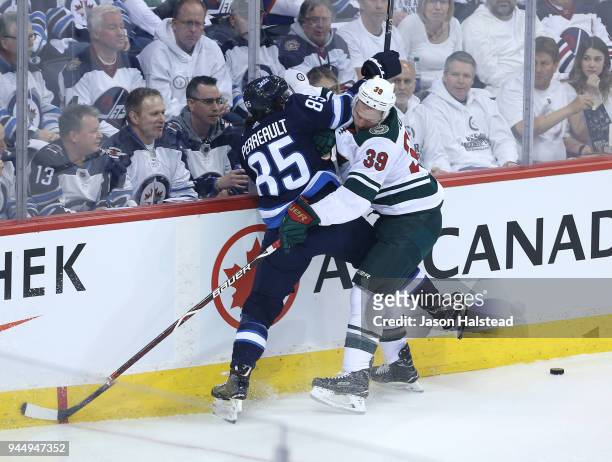 Mathieu Perreault of the Winnipeg Jets battles Nate Prosser of the Minnesota Wild in Game One of the Western Conference First Round during the 2018...