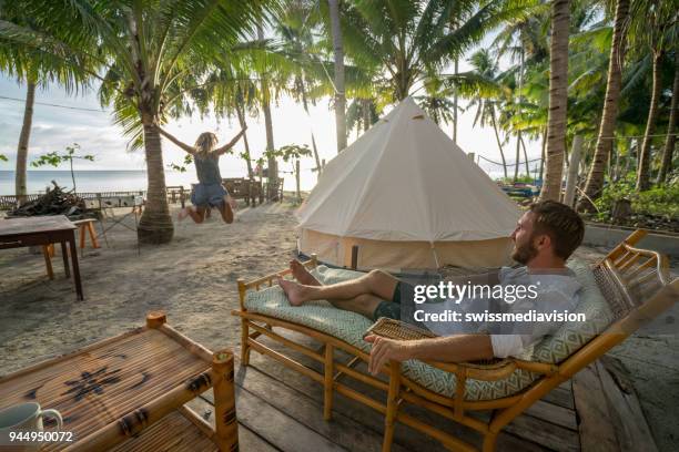 young couple relaxing in glamping campground in tropical scenery - casal heterossexual imagens e fotografias de stock