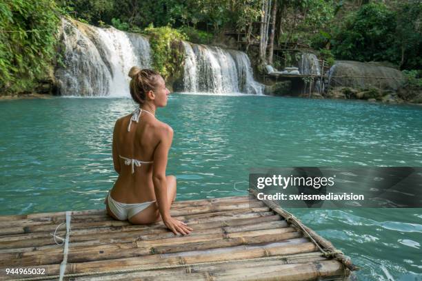 生活を楽しんでいる熱帯の滝で竹いかだに乗って若い女性 - bamboo raft ストックフォトと画像