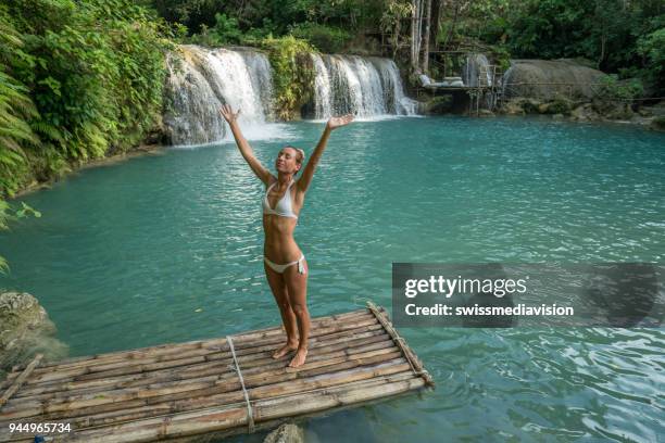 giovane donna su zattera di bambù che abbraccia la natura alla cascata nella foresta pluviale, braccia tese - bamboo raft foto e immagini stock