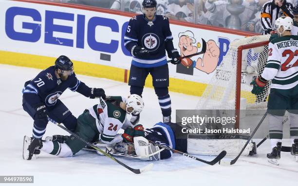 Joe Morrow of the Winnipeg Jets pulls Matt Dumba of the Minnesota Wild off Jets goalie Connor Hellebuyck in Game One of the Western Conference First...