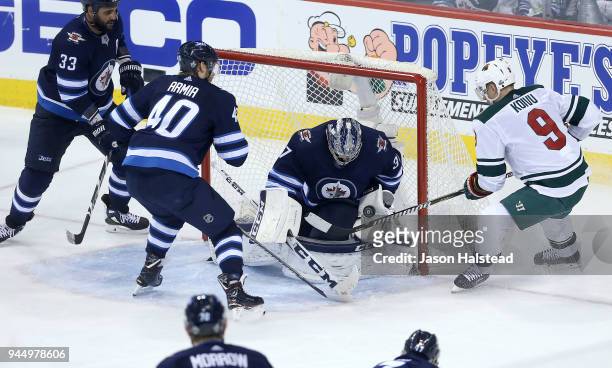 Connor Hellebuyck of the Winnipeg Jets makes a save off Mikko Koivu of the Minnesota Wild as Dustin Byfuglien and Joel Armia of the Winnipeg Jets...