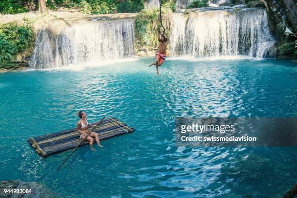 young couple playing at beautiful waterfall in the philippines - philippines women stock pictures, royalty-free photos & images