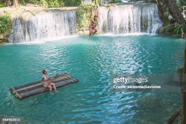young couple playing at beautiful waterfall in the philippines - waterfall jump stock pictures, royalty-free photos & images