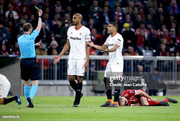 Steven NZonzi of FC Sevilla receives a yellow card from referee William Collum of Scotland while Gabriel Mercado of FC Sevilla protests during the...