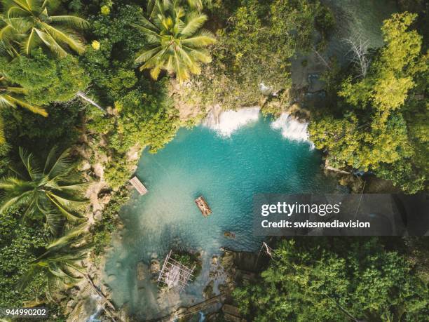 drone shot aerial view of young woman bamboo rafting at tropical waterfall - mind over matter stock pictures, royalty-free photos & images