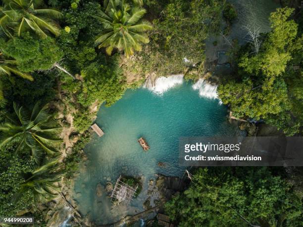 drone shot aerial view of young woman bamboo rafting at tropical waterfall - philippines stock pictures, royalty-free photos & images